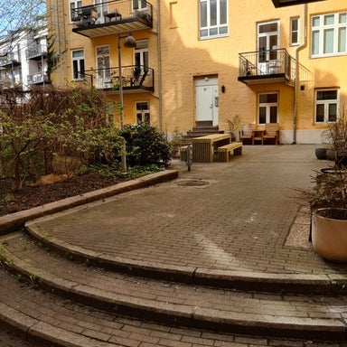 Bakgård med benker og krukker på brostein