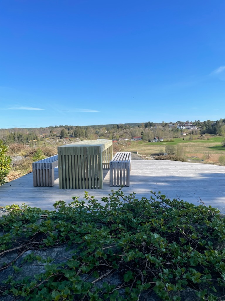 Bordgruppe i tre på stor terrasse med utsikt over landskap
