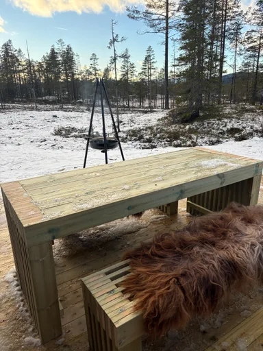 Langbord i tre på terrasse med snø og bålpanne