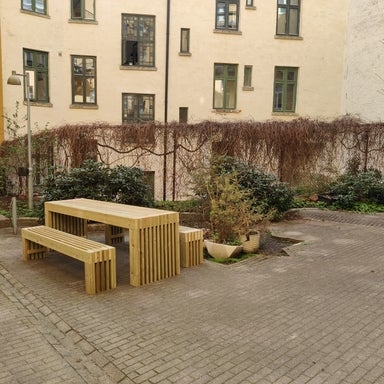 Bordgruppe i lys furu med to benker i bakgård