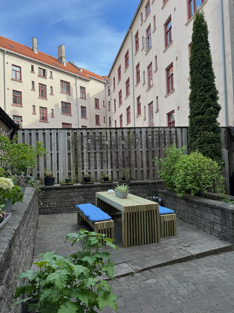 Spilebord med benker og blå puter i bygård