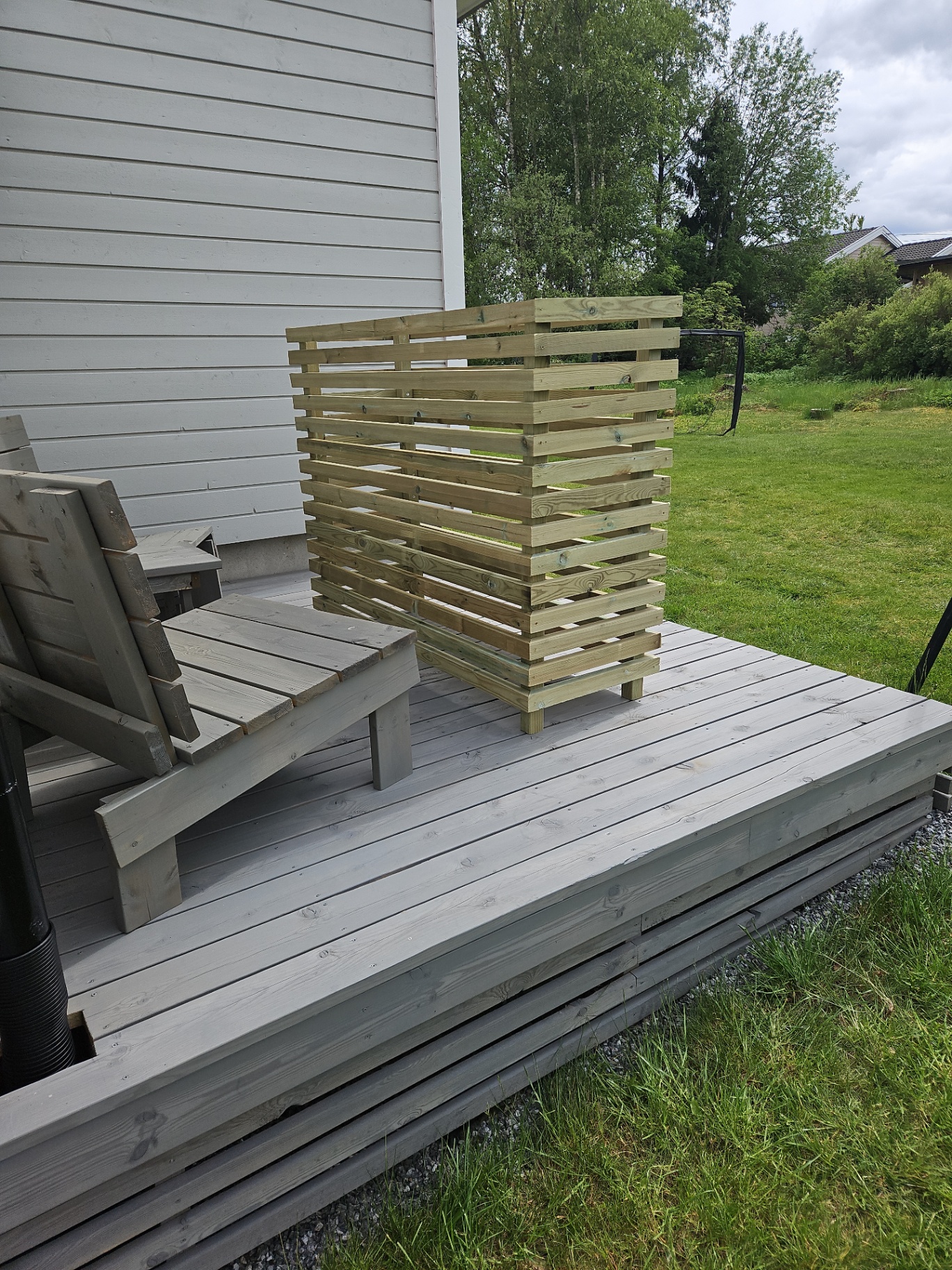 Søppelkassestativ i spiler på grå terrasse ved husvegg