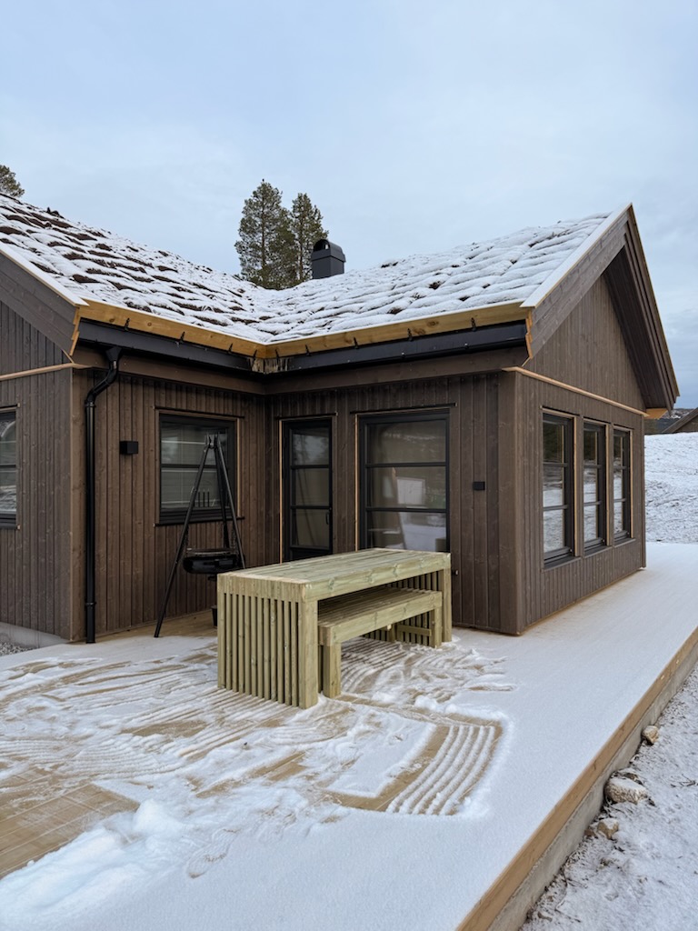 Hytte med stor terrasse og bordgruppe i tre